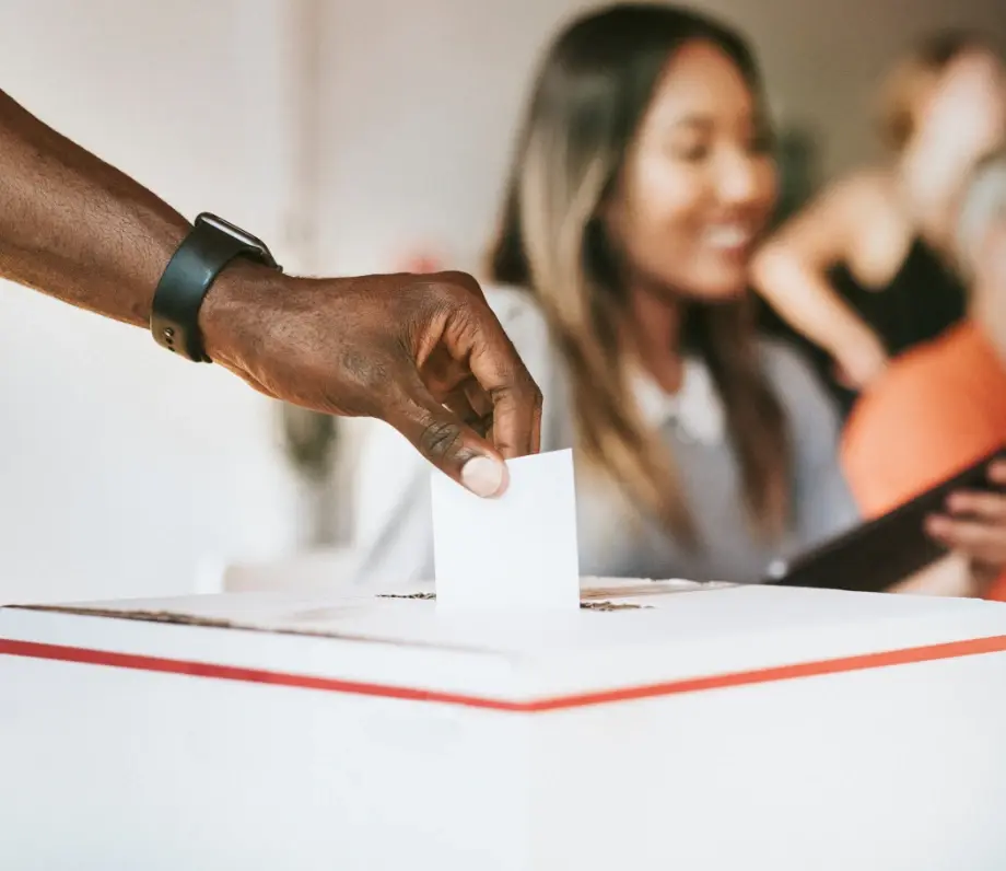 hand putting vote into a ballot box
