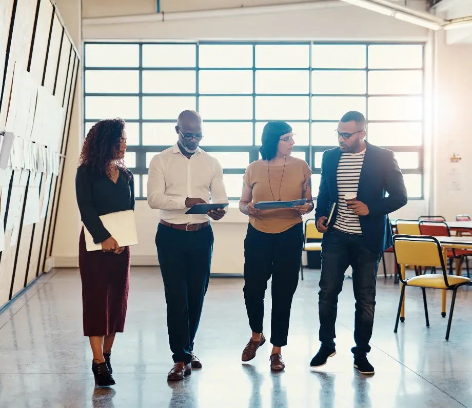 Four people walking with tablets and notes